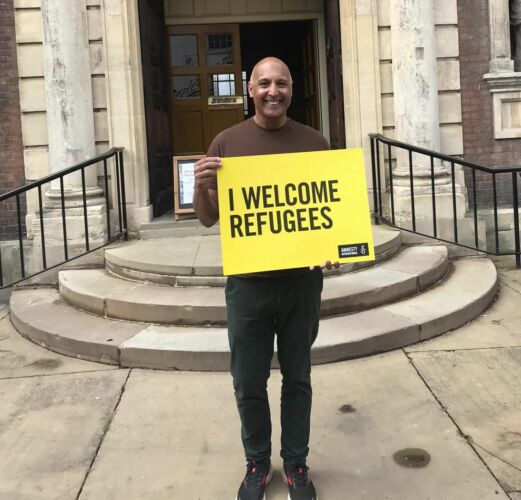 Man holding a sign saying 'I Welcome Refugees'